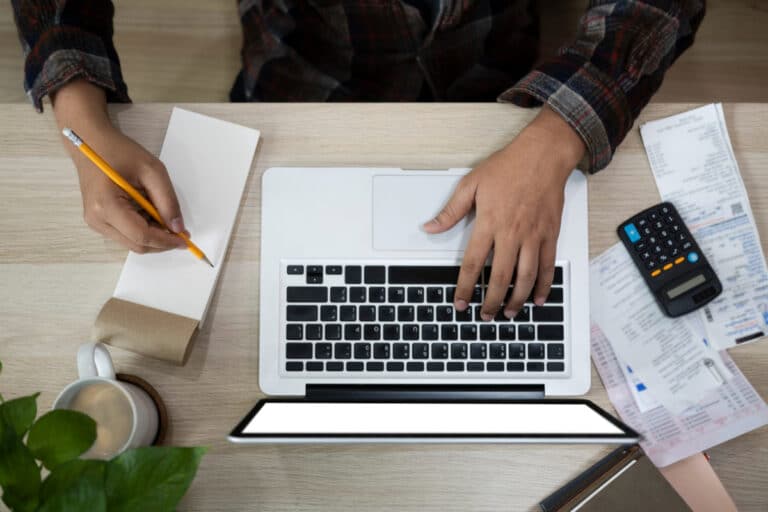 Cálculo del presupuesto de una tienda online con ordenador y calculadora sobre un escritorio